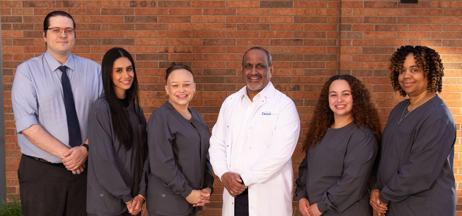Dr. Rahman and team posing in front of brick wall